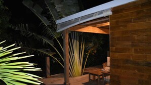An outdoor wooden deck with a covered seating area, surrounded by tropical plants. - KAZATIPUNCH - CHARMING BUNGALOW IN TROPICAL GARDEN (st francois)