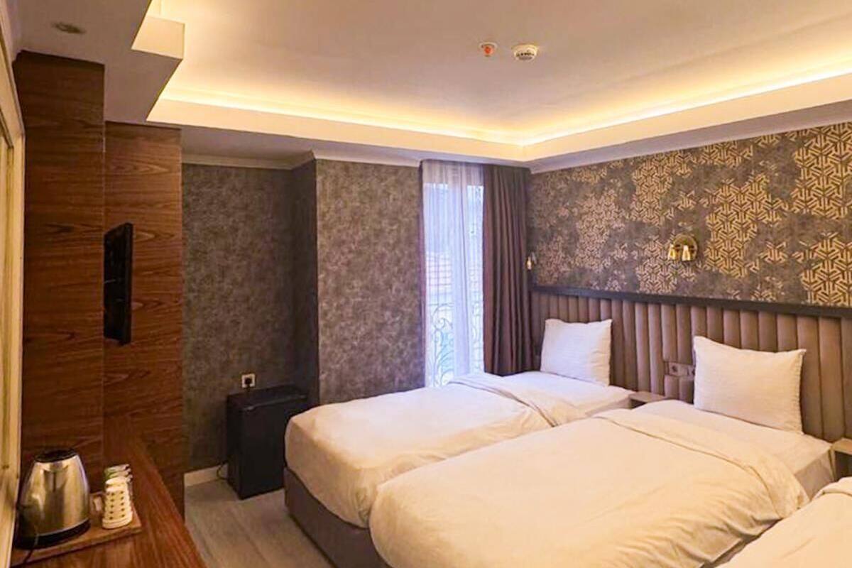 A hotel room with two beds, a wooden desk, and a patterned wall.