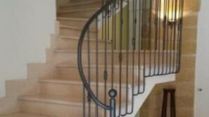 A staircase with a metal railing, leading to a landing with a view of a stone wall. - B&B Manzoni Resort (Brindisi)
