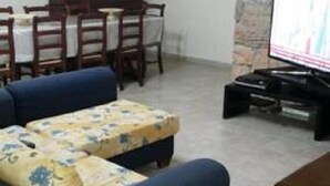 A living room with a sofa set, a television, and a stone wall. - B&B Manzoni Resort (Brindisi)
