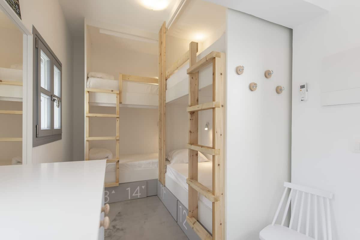 Una habitación con literas, un escritorio blanco y una silla blanca.