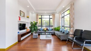 A modern living room with a TV, sofa, coffee table, and seating area. - Vihomes Villa (Ho Chi Minh City)