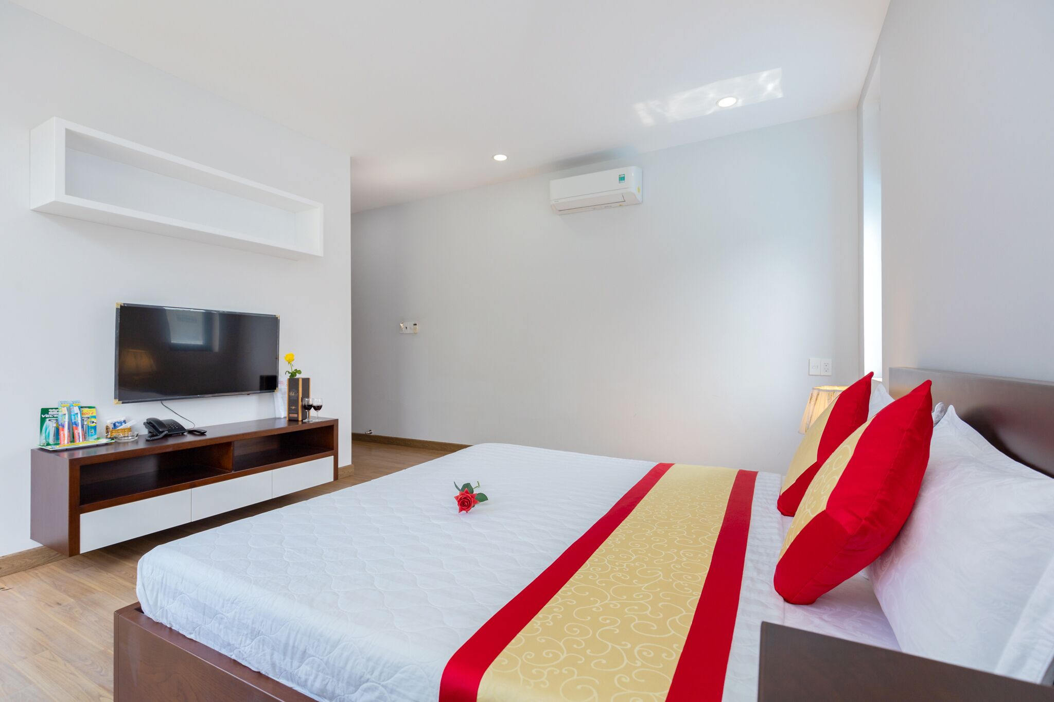 Ein Hotelzimmer mit einem Bett, einem Fernseher, einem Nachttisch und einem Regal mit Pflegeprodukten.