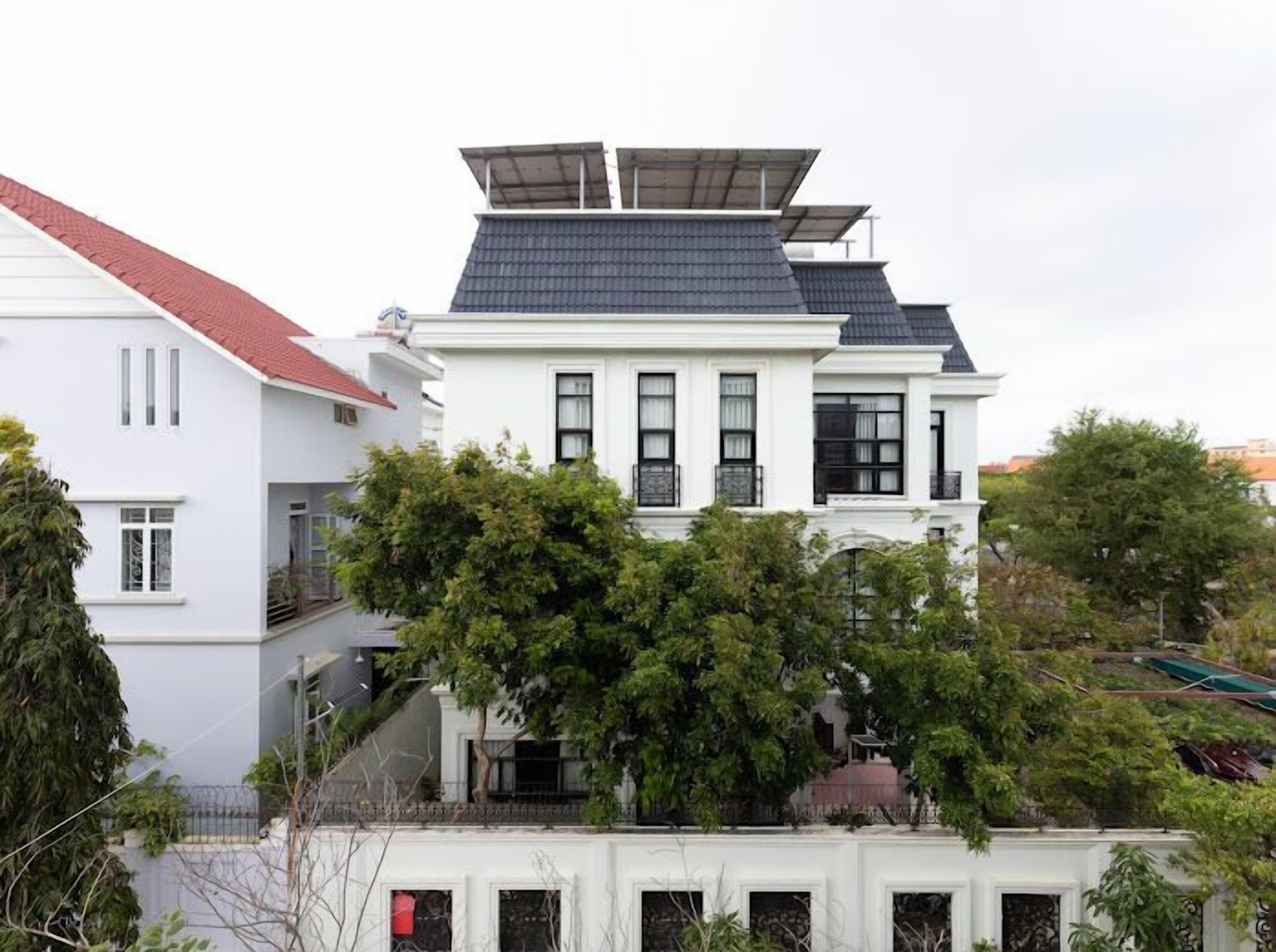 A white building with a red roof and solar panels on the roof.