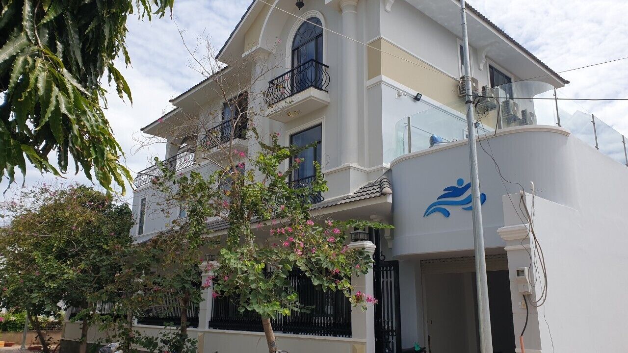 A two-story building with balconies, a large window, and a visible logo on the side.