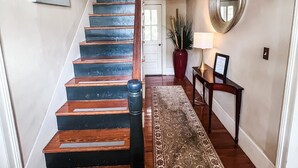 Un escalier avec des marches en bois et une rampe noire, menant à l’étage supérieur.