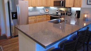 Una cocina moderna con armarios de madera, electrodomésticos de acero inoxidable y encimera de granito.