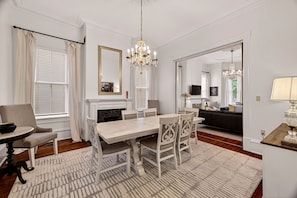 Un espace repas agrémenté d’un lustre, d’une cheminée et offrant une vue sur le salon.