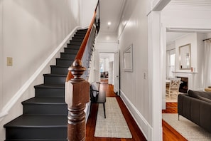 Un escalier avec des balustrades en bois, un couloir avec un tapis et un coin repas avec une table et des chaises.