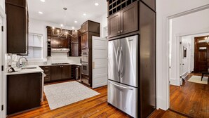 A modern kitchen with dark wood cabinets, stainless steel appliances, and a wooden floor. - Newly Renovated 1890 Victorian Downtown Home w/ Heated Pool by Lucky Savannah (Savannah)