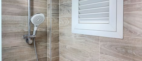 Een douche met een handdouche en een bediening aan de muur.