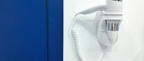 A white hair dryer mounted on a wall with a blue door nearby.