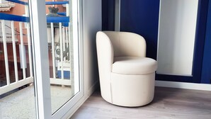 A corner room with a white cushioned chair, a sliding glass door, and a view of a balcony with a railing. - Hotel Flats Friends Mar Blau (Benidorm)