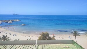 A beach with clear blue water, a rocky outcrop, and a distant island. - Hotel Flats Friends Mar Blau (Benidorm)