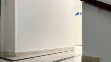 A hallway with white walls and a tiled floor, leading to a room with a door labeled '506'.