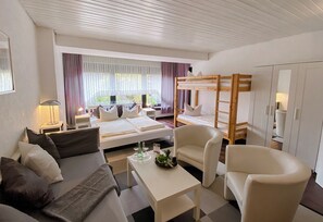 Une chambre d’hôtel moderne équipée d’un canapé, d’une table à manger, d’un lit superposé et d’une armoire.