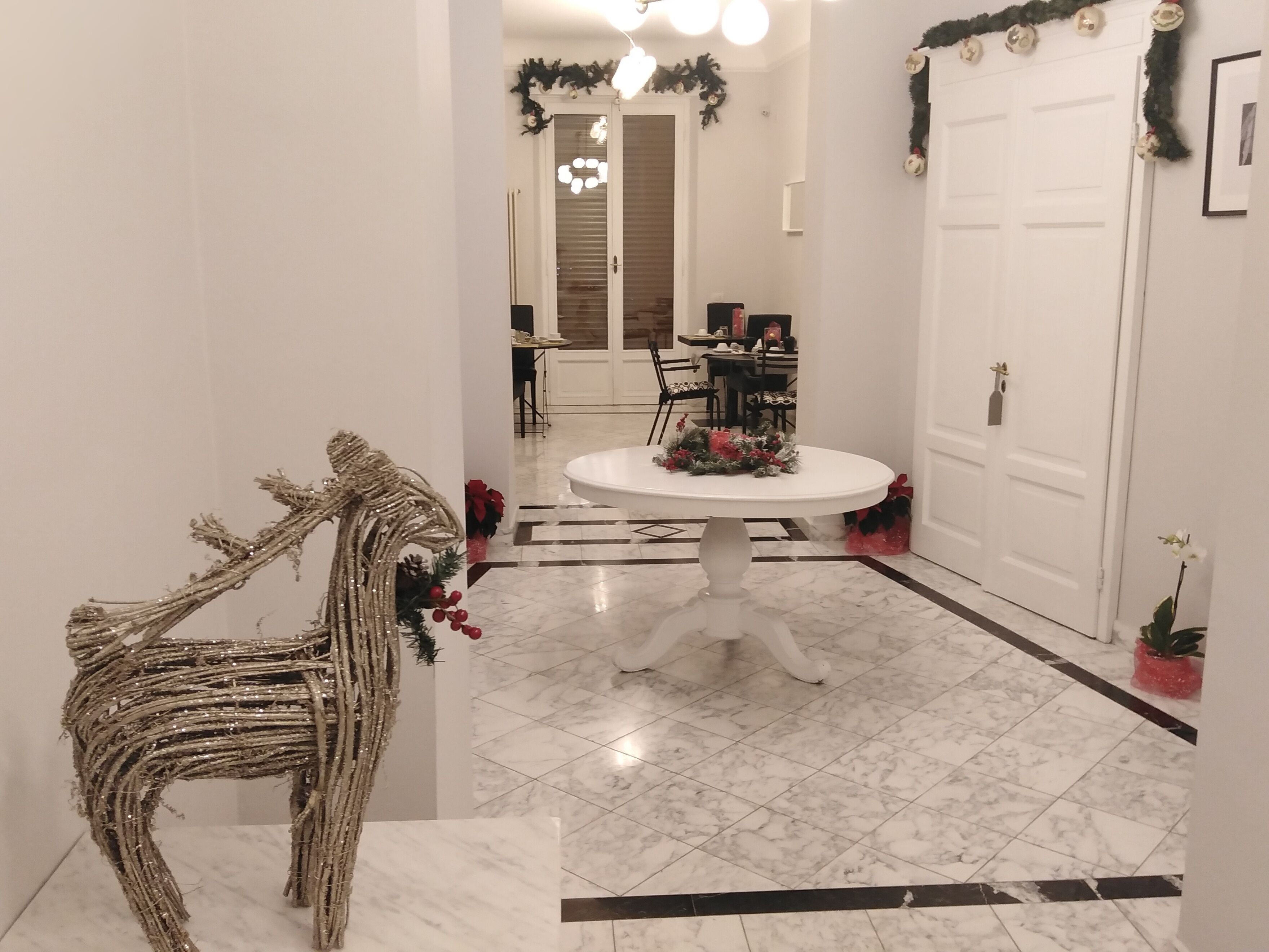 Un pasillo con una puerta blanca, un área de comedor con una mesa redonda y una escultura decorativa de un caballo.