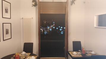 Un coin repas avec deux tables dressées pour le repas, un radiateur, des tableaux encadrés au mur et une porte décorée pour les fêtes.