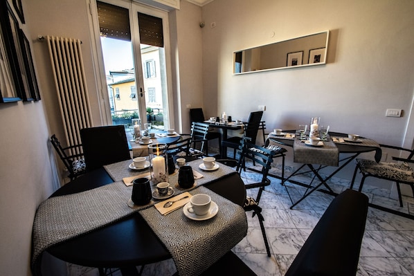 Comedor con una mesa dispuesta para cuatro, con platos, vasos y cubiertos. Hay sillas alrededor de la mesa y una ventana ofrece vistas al exterior.