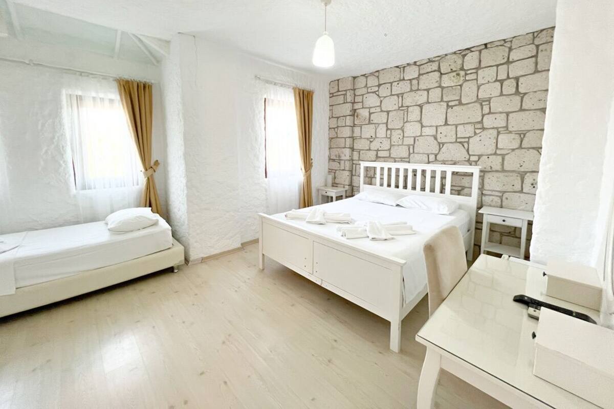 A room with a bed, a small table, and a window with curtains.