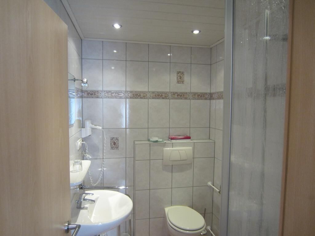 A bathroom with a sink, toilet, and shower area.