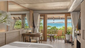 A modern hotel room with a large bed, a desk with a lamp, a small table with chairs, and a view of the sea. - Vivere Azure (Mabini)