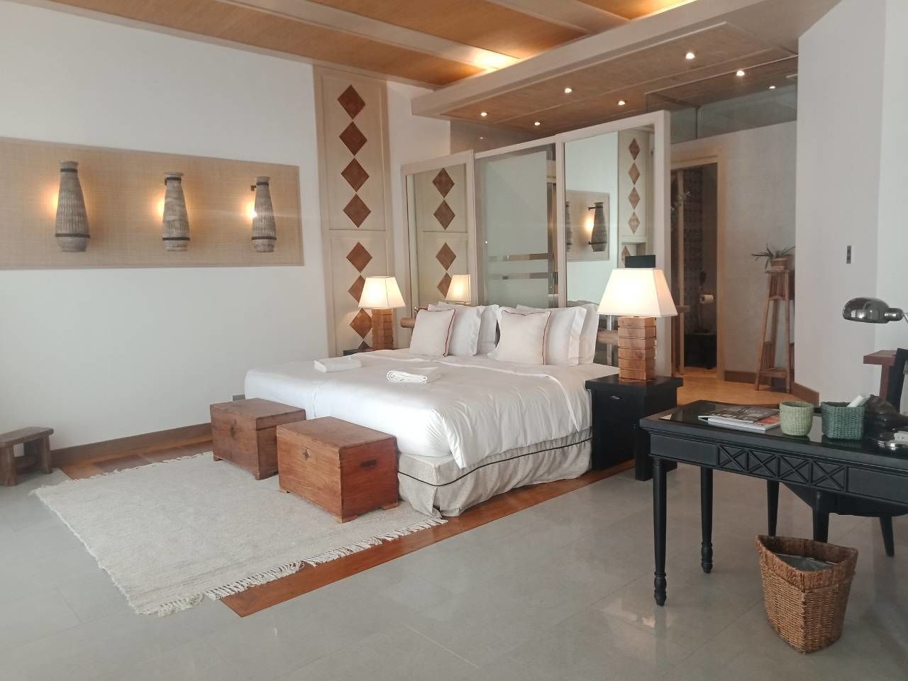 A bedroom with a bed, bedside tables, a desk, and a mirror.