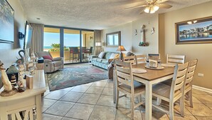 A spacious living room with a dining area, large windows offering a view of the ocean, and a ceiling fan. -  Label Day Weekend Now Available 1st Floor-XXL Oceanfront Balcony OC Tower South (Myrtle Beach)