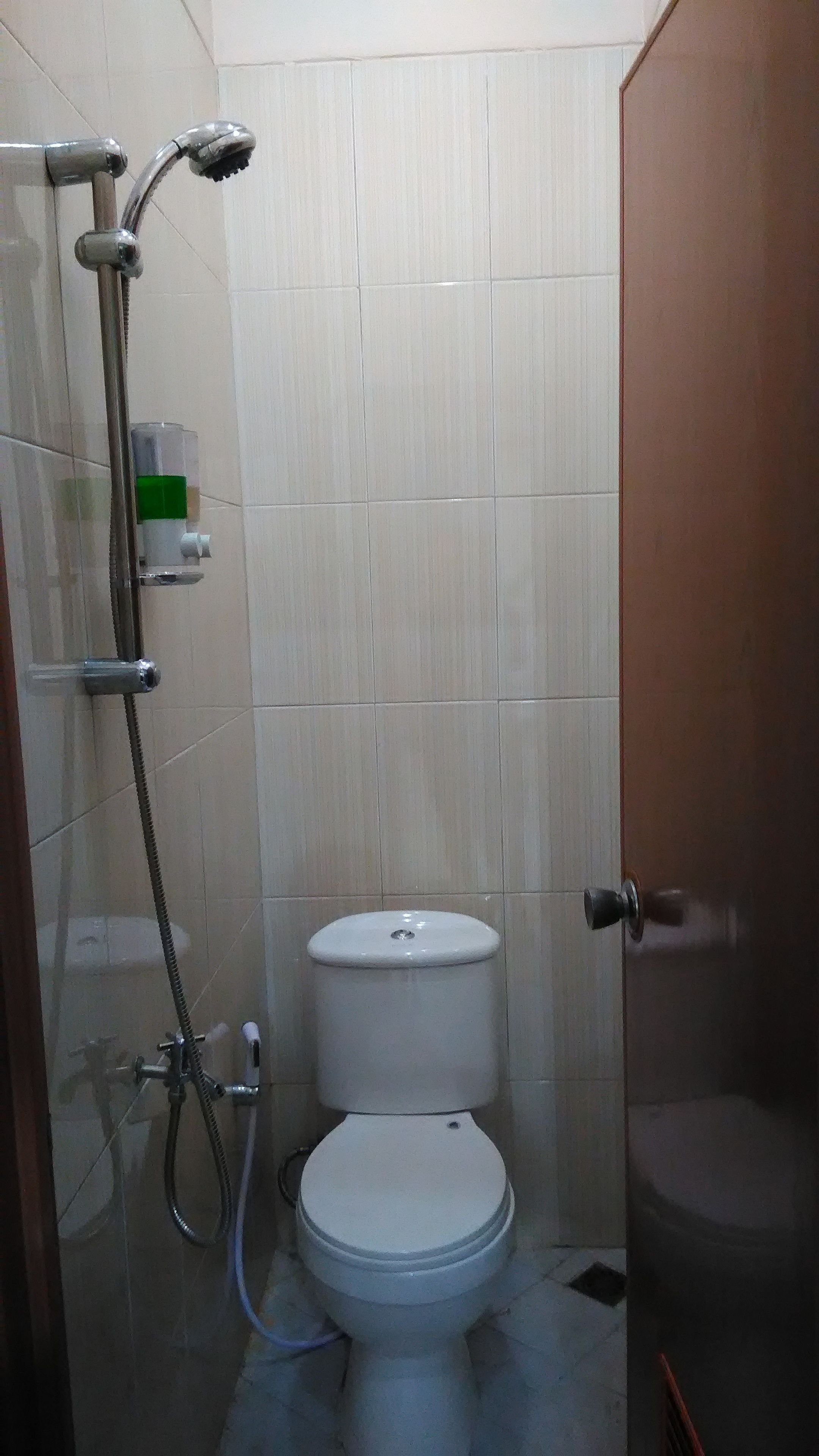 A small, tiled bathroom with a toilet, a shower, and a glass door.