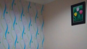 A bedroom with a bed, a headboard, and a wall with a floral pattern. - Adaya Hotel (Bekasi)