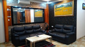 A modern living room with two black leather sofas, a wooden coffee table, and a large mirror. - Adaya Hotel (Bekasi)