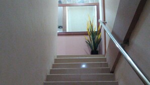 A staircase with a handrail, leading to a landing with a potted plant. - Adaya Hotel (Bekasi)