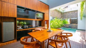 A modern kitchen with wooden cabinets and a built-in refrigerator. - Agranusa Signature Villa (Nusa Dua)