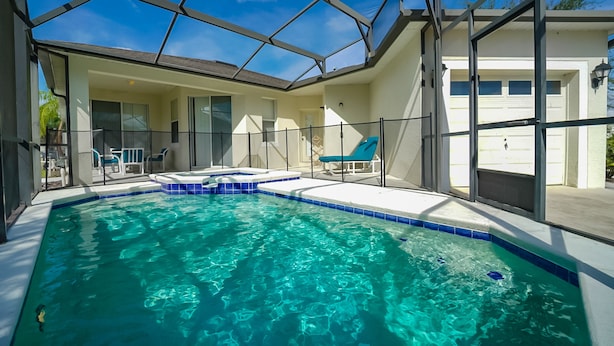 Una piscina con techo de vidrio, sillas de descanso y un garaje.
