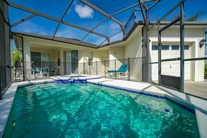 A swimming pool with a glass ceiling, lounge chairs, and a garage. - Pool Home with Spa on Gated Resort Community Close to WDW (Kissimmee)