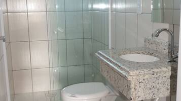 Un baño con inodoro, lavamanos y zona de ducha.