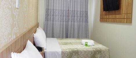 A hotel room with two beds, a TV on the wall, and a curtain.