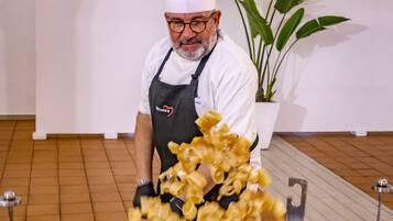 Un xef cuinant pasta en un gran wok sobre un fogó portàtil.