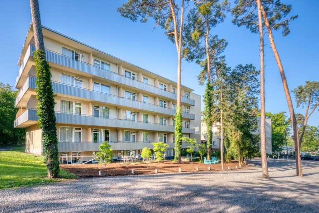 A multi-story hotel with a flat facade, balconies, and a landscaped courtyard.