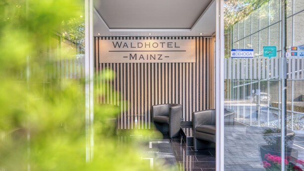Ein Empfangsbereich mit einem Schild, auf dem 'WALDHOTEL - MAINZ-' steht.