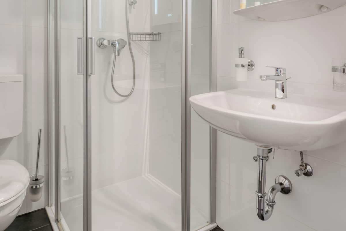A modern bathroom with a glass-enclosed shower, a white sink, and a mirror above the sink.