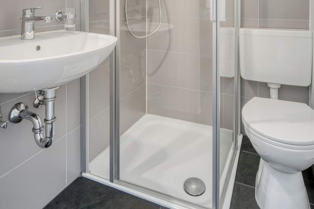 A modern bathroom with a glass-enclosed shower, a white sink, and a toilet.
