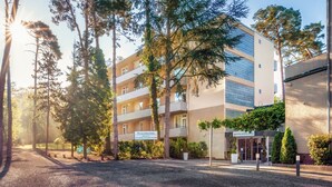 Ein Hotel mit einer modernen Fassade, mehreren Balkonen und einem gepflegten Gartenbereich.