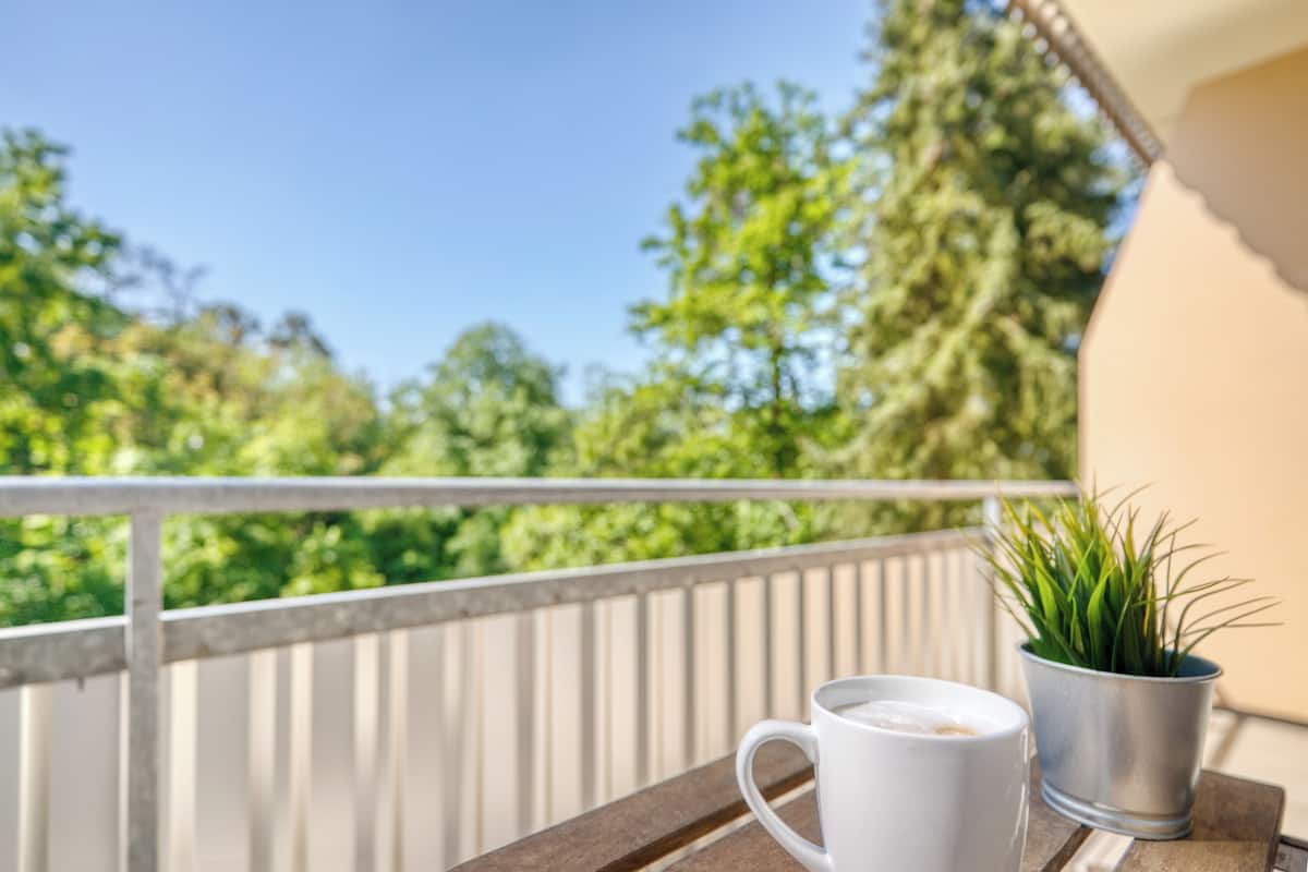 A balcony with a railing, a white mug, and a small potted plant.