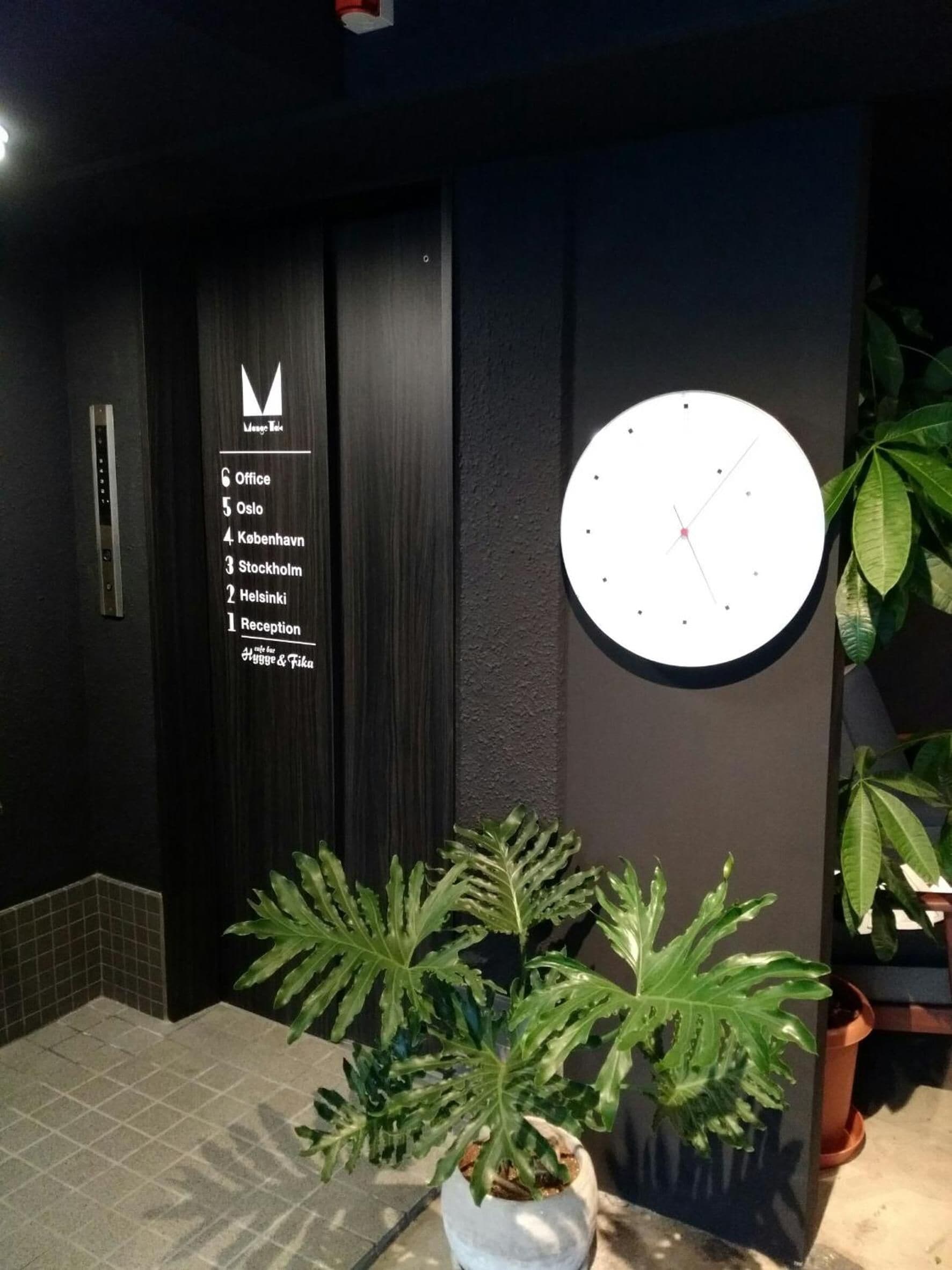 A reception area with a wall-mounted clock and a sign listing office locations.