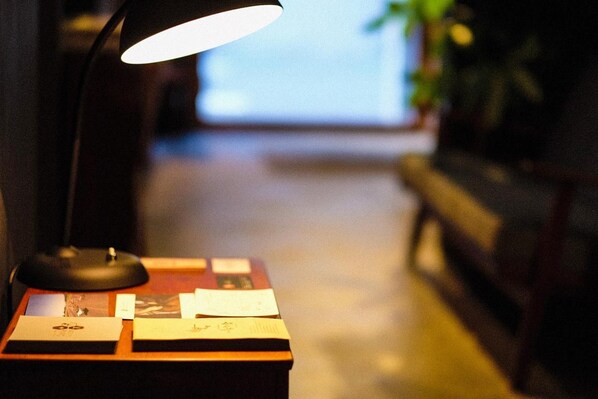 A desk with a lamp, papers, and a small box, leading to a blurred interior space.