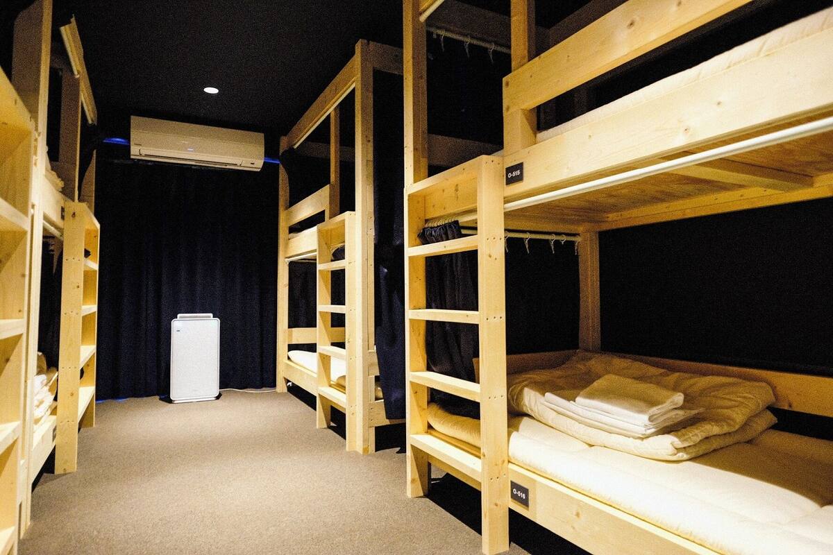 Ein Zimmer mit Etagenbetten, einer weißen Klimaanlage und einem schwarzen Vorhang.