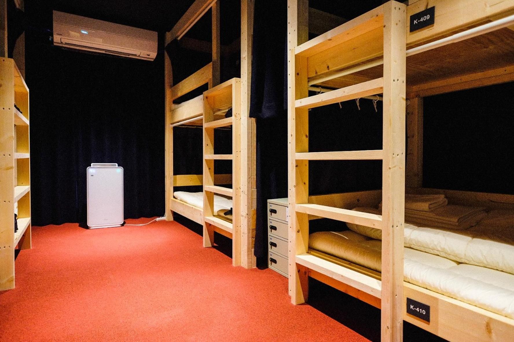 A room with bunk beds, a small white appliance, and a red carpet.