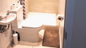 A bathroom with a toilet, sink, shower, and a towel rack. - Metropol Inn (Hounslow)
