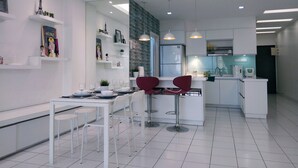 A modern kitchen with white cabinetry, a central island with bar stools, and a dining area with a white table and chairs. - Plaza Manjalara with 2 bedrooms (Kuala Lumpur)